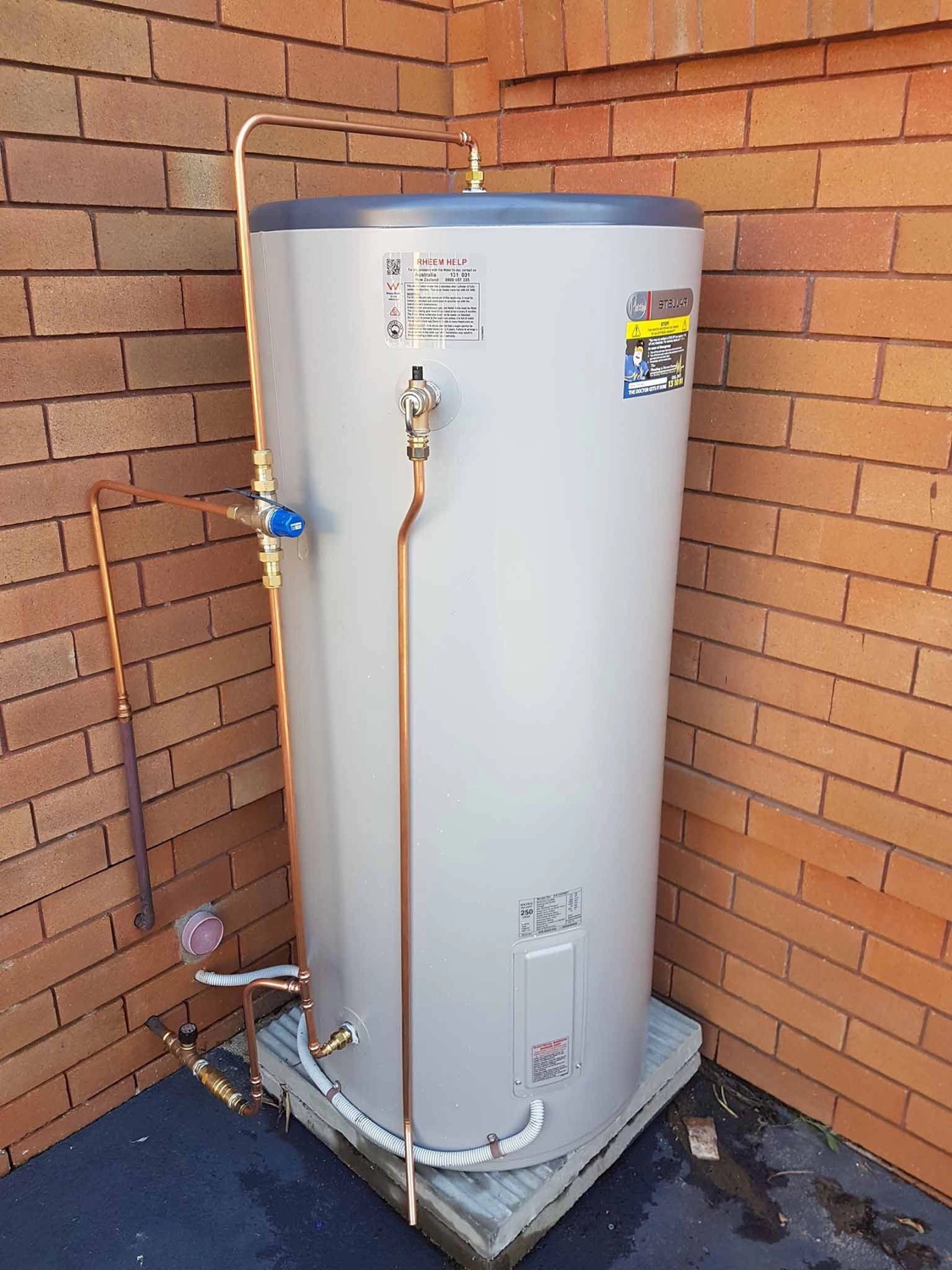Rheem electric storage hot water system installed against a brick wall